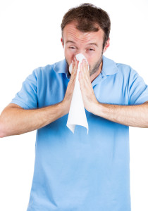 Man with allergy, cold, blowing nose with a tissue
