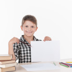 cute boy sitting at table and writing.