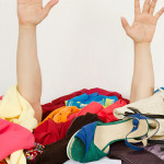 Man hands reaching out for help from a big pile of woman clothes