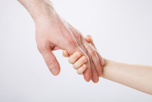 Child holding father's hand, closeup shot on grey background